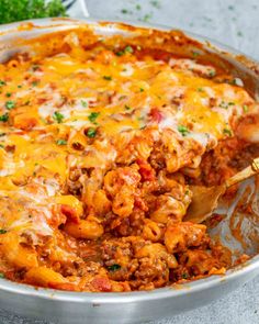 a casserole dish with meat, cheese and sauce being scooped from the pan