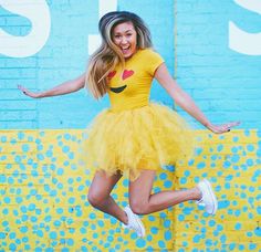 a girl in a yellow dress jumping up into the air