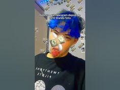 a young man with blue hair has money taped to his face and is wearing a t - shirt