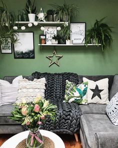 a living room filled with furniture and lots of plants on the wall above it's couch