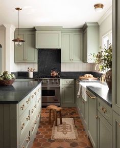 a kitchen with green cabinets and black counter tops, an oven, sink, and stools