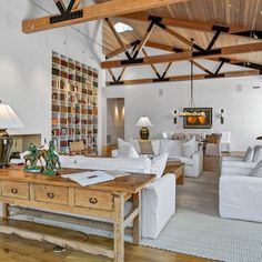 a living room filled with white furniture and lots of bookshelves on the walls