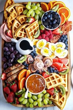 a wooden platter filled with waffles, fruit, and other food items