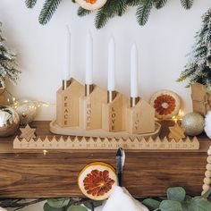 a table topped with candles and figurines on top of a wooden shelf next to greenery