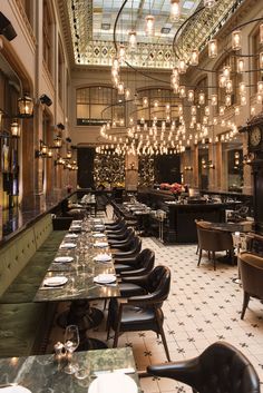 a restaurant with tables, chairs and chandeliers hanging from the ceiling above them