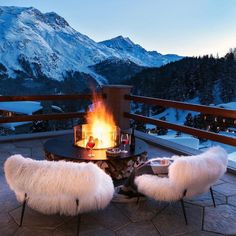 two chairs sitting next to a fire pit on top of a patio