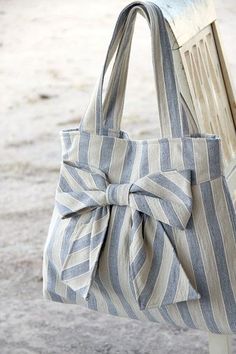 a gray and white striped bag sitting on top of a wooden bench