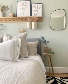 a bed with white sheets and pillows next to two framed pictures on the wall above it