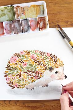 someone is painting a hedge on paper with watercolors and paintbrushes next to it