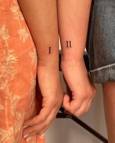 two people holding hands with tattoos on their arms and one has the letter i in it