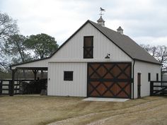 a white barn with a brown door and windows