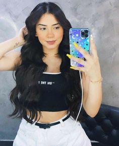 a woman with long black hair is holding up her cell phone to take a selfie