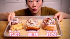 a woman holding up three pastries on a tray with cinnamon rolls in each one