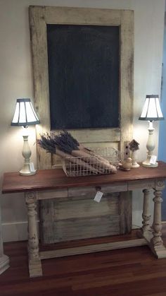 a wooden table topped with two lamps and a chalkboard