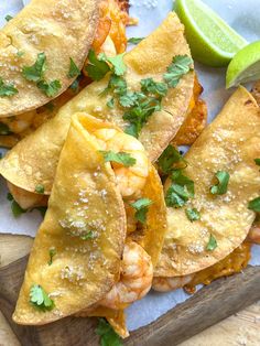 some food is laying out on a cutting board next to a lime wedge and chips