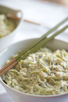 two chopsticks sticking out of a bowl of noodles