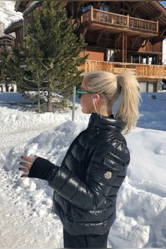 a woman standing in the snow near a house