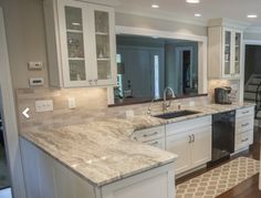 a kitchen with marble counter tops and white cabinets