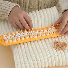 a person holding a yellow and white knitted object with two hands on top of it