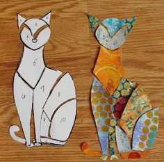 two paper cats sitting on top of a wooden table