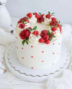 a white cake topped with raspberries and whipped cream