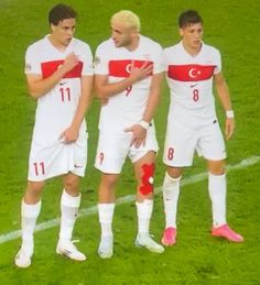 three men in white and red uniforms standing on a soccer field