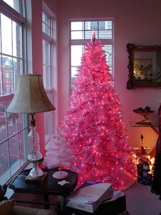 a pink christmas tree sitting in the corner of a living room next to a window