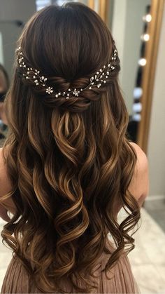 the back of a woman's head with long, wavy hair and flowers in her hair