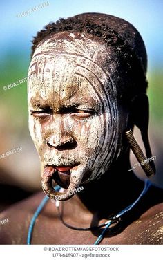 an african man with white paint on his face and nose, wearing a headdress