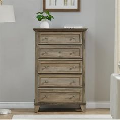 a wooden chest of drawers sitting next to a white rug in a room with gray walls