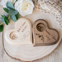 two wooden heart shaped magnets with wedding rings on them and flowers in the background