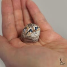 a hand holding a tiny cat figurine in it's palm