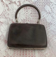 This is such an amazing little necessaire from maybe 40's,maybe earlier. Rare not just in itself,but the amazing condition for the age. The outside is in very soft brown leather with matching handle and framed in silver metal(maybe chrome) with a kiss lock opening. Opens to reveal a purple silk lining and a pop up centre housing ten personal vanity items,seven of which have mother of pearl handles. Everything in great order with some silvered bits showing a few minor age marks which I am sure are removable. Measures 13.5 x 9 cms not including handles. A very special Vintage item. Vintage Handbag, Toiletry Kit, Vanity Case, Purple Silk, Soft Brown, Toiletry Storage, A Kiss, Vintage Handbags, Travel Case