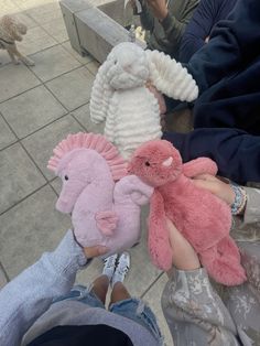 three stuffed animals are sitting on someone's lap while another person holds them in their hand