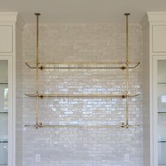 a bathroom with white tile and gold fixtures on the wall, along with glass cabinets