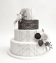 a three tiered cake decorated with flowers and leaves on a white stand against a plain background