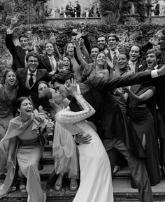 a group of people standing next to each other in front of a building with their hands up