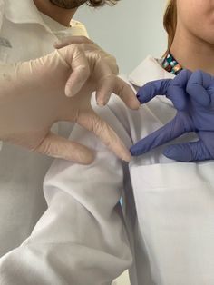 two people in white lab coats and blue gloves