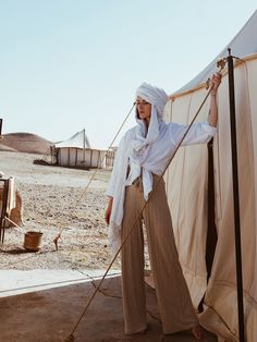 a woman standing next to a tent in the desert