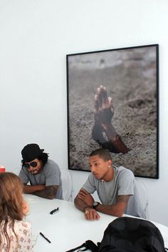 a group of people sitting around a white table in front of a painting on the wall