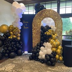 the balloon arch is decorated with black, gold and white balloons