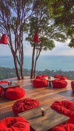 an outdoor seating area with red bean bags on the floor and trees in the background