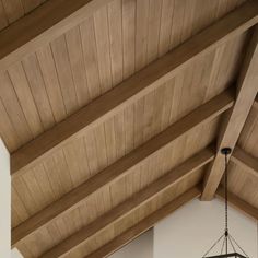 a clock hanging from the side of a wooden ceiling