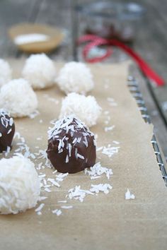 chocolate truffles with coconut sprinkles on a piece of parchment paper