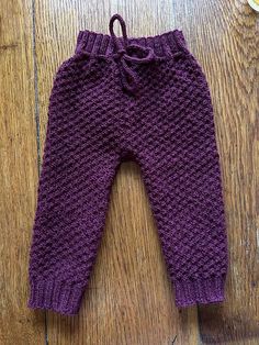 a purple knitted pant sitting on top of a wooden floor