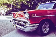 an old red car is parked on the street