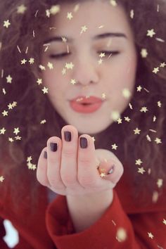 a woman holding her hand up to her face with stars on it