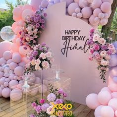 a birthday party with balloons and flowers on the wall