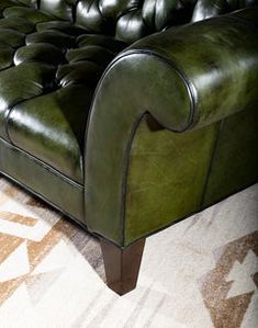 a green leather couch sitting on top of a rug