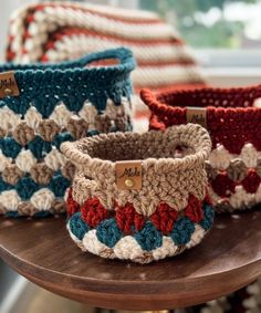 three crocheted baskets sitting on top of a wooden table next to each other